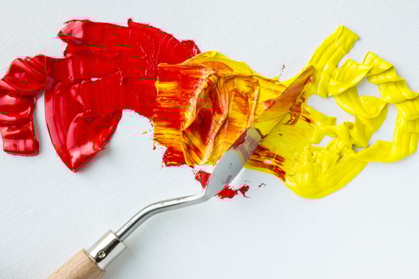 Palete knife mixing red and yellow oil paint